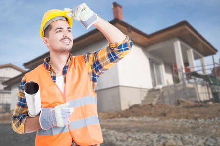 Outdoor portrait of young builder with house project looking cheerful up with copy space