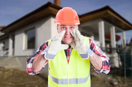 Constructor on construction site with protection equipment screaming or announcing somethingの写真素材