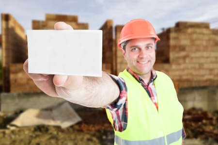Successful male builder holding blank visit card in closeup as professional construction services conceptの写真素材