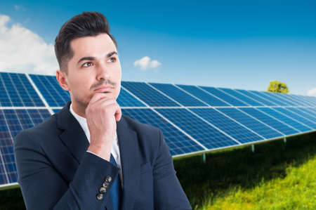 Portrait of thoughtful businessman standing outside near solar panels with copy spaceの写真素材