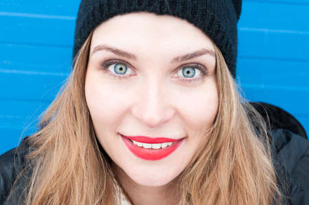 Close-up of attractive woman wearing winter clothes on blue backgroundの写真素材