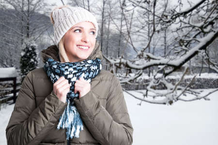 Young smiling woman feeling happy outside in frozen snow and looking one side with copy space