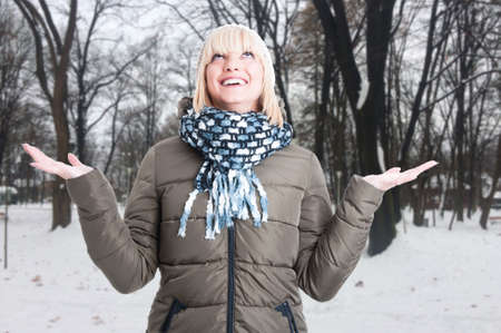 Portrait of pretty girl with open palms enjoying snow outdoors with advertising area
