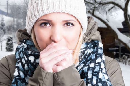 Close-up portrait of attractive young female outdoors in the snow with frozen handsの写真素材