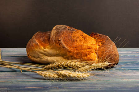 Closeup of fresh and organic bread on wooden table and wheat ear as fibers concept