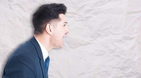 Side portrait of angry manager screaming out loud at somebody on crumpled paper background with text...
