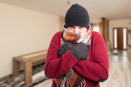 Cold sick man with influenza dressed in warm clothes inside the house with copy spaceの写真素材