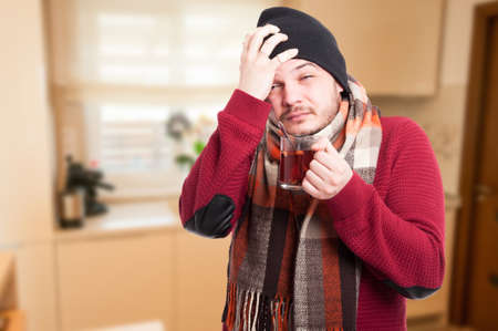 Man with flu and fever holding cup of healing tea into the house with copy spaceの写真素材