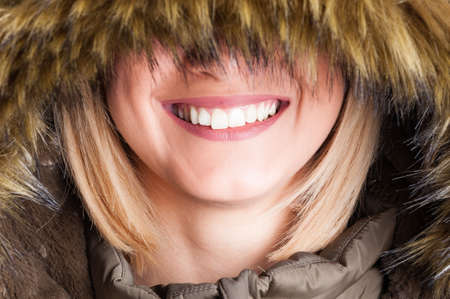Close-up of blonde girl with faux fur hood with eyes covered am smiling happyの写真素材