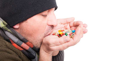 Closeup of sick man swallow pills from his hand and doing medication abuse on white background with text areaの写真素材