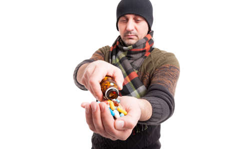Exhausted male with flu taking medicines from glass bottle on white studio backgroundの写真素材