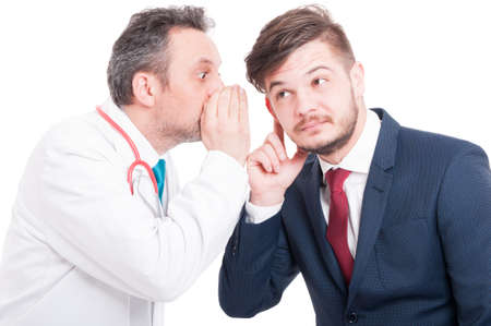 Male doctor telling a secret or whispering something to curious businessman isolated on white backgroundの写真素材