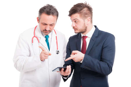Young manager with medic or doctor looking at something on smartphone isolated on white backgroundの写真素材