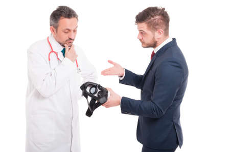 Male doctor with businessman holding futuristic device on white studio backgroundの写真素材