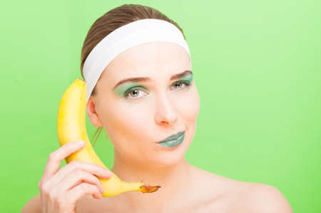 Woman with banana having fun on green background in closeup viewの写真素材