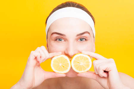 Beautiful woman face with juicy lemon before her mouthの写真素材