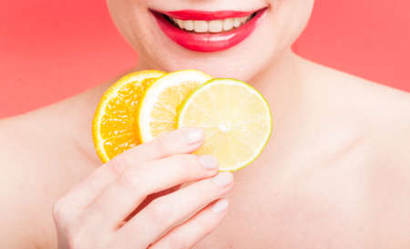 Closeup of orange slices, lemon and lime in female hand on red backgroundの写真素材
