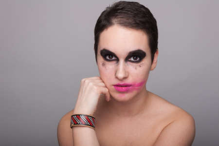 Portrait of female face with dirty colored makeup isolated on grey backgroundの写真素材
