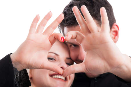 Young couple holding hands in shape of heart in close-up view on white backgroundの写真素材