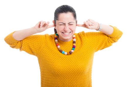 Pretty woman with fingers in ears acting like a deaf on white studio background