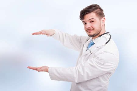 Handsome medic holding something big between hands with copyspace on blue backgroundの写真素材