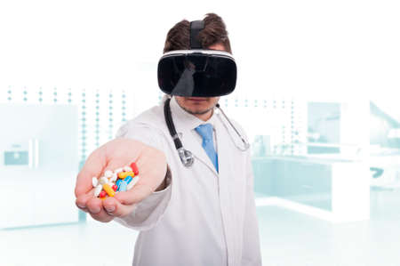 Modern medic with vr headset holding pills and vitamins in hand in the hospitalの写真素材