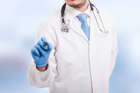 Male doctor writing something with marker on empty screen isolated on blue backgroundの写真素材