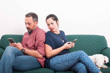 Young female looking over her shoulder at what his boyfriend is texting on phoneの写真素材