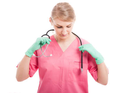 Female medical nurse or doctor putting on her stethoscope preparing for shift isolated on white...