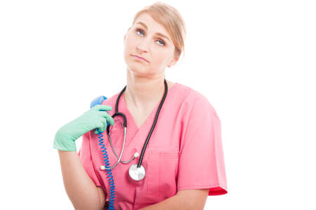 Medical nurse lady holding telephone receiver looking bored isolated on white background with copy text spaceの写真素材