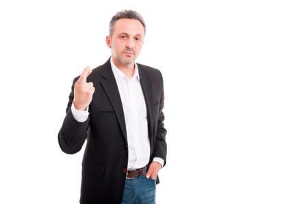 Serious businessman holding his finger crossed as sign of bad luck on white background with advertising areaの写真素材