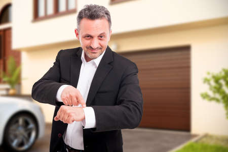 Young realtor pointing at his watch showing hand clock as real estate buying conceptの写真素材