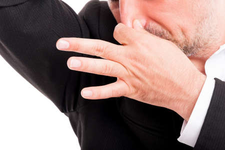 Sweaty businessman is disgusted of unpleasant smell from his underarm in close-up view