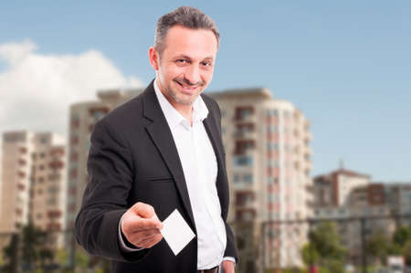 Young real estate agent showing blank card for customer recommendation