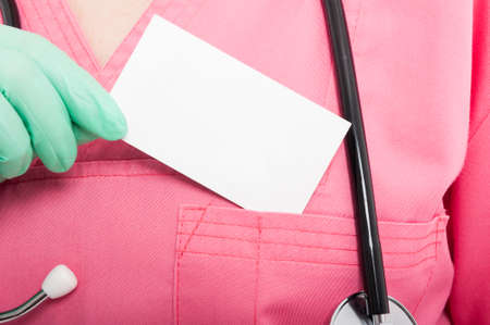 Close-up of medical nurse lady holding blank business card isolated on white backgroundの写真素材