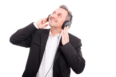 Smiling young man with headphones listening music and looking up isolated on whiteの写真素材