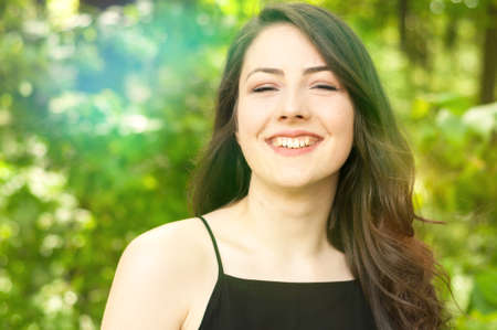 Closeup portrait or shot with flares of cheerful lady with bright smile in the park