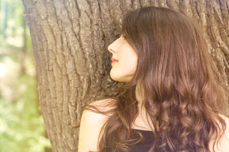 Woman portrait with sun flare in side view posing outdoor. Summertime mood concept with copy text spaceの写真素材