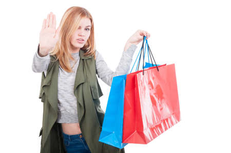 Shopping girl with colored gift bags rising up her palm as stop sign conceptの写真素材
