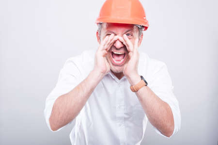 Portrait of architect wearing  hardhat screaming out loud on grey backgroundの写真素材