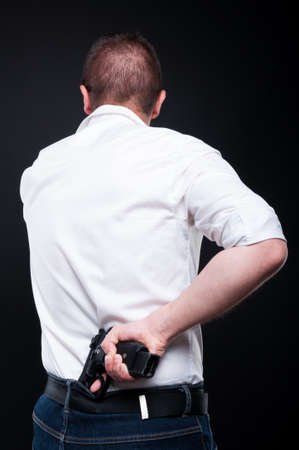 Caucasian gangster concealing his handgun behind his back as crime and violence conceptの写真素材