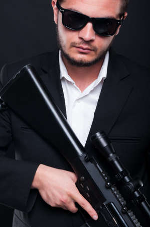 Portrait of man with machine gun in hands on dark studio backgroundの写真素材