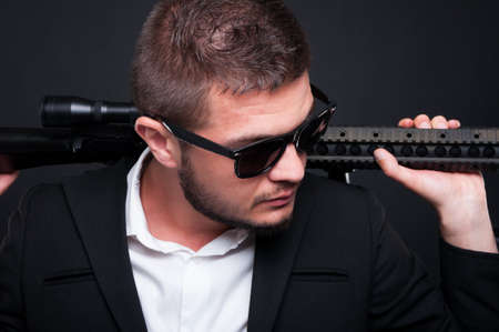 Armed gangster man with weapon on dark background in close up view