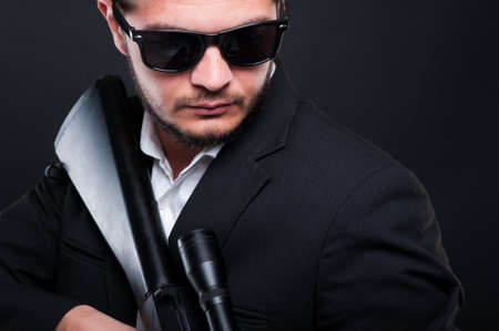 Mafia gangster man in suit and sunglasses with rifle as violence and crime conceptの写真素材
