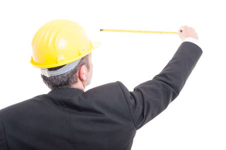 Back view of architect posing measuring with ruler tape wearing yellow hardhat isolated on white backgroundの写真素材