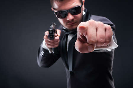 Young criminal or gangster with armed pistol pointing and threatening youの写真素材