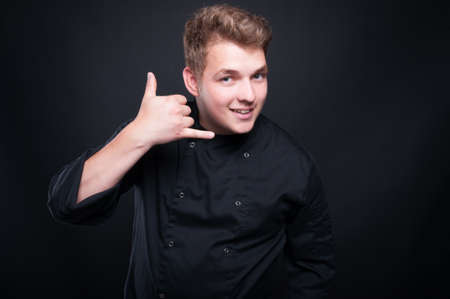 Young caucasian chef  making call me gesture as catering or food order conceptの写真素材
