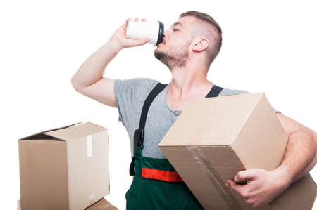 Mover man holding cardboard box and drinking coffeeMover man holding cardboard box and drinking...