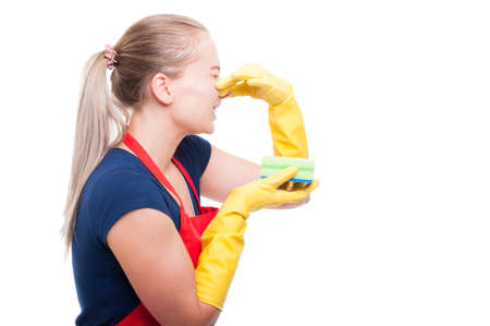 Maid woman with stinky cleaning sponge holding her nose looking disgusted