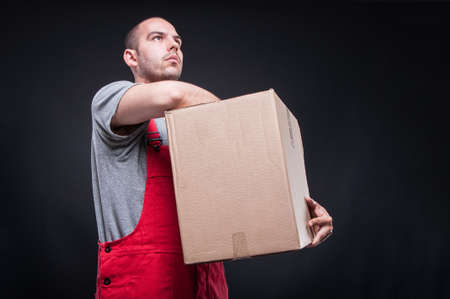 Low angle of mover man holding box looking up on black background with copy text space